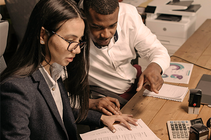 Two people looking over paperwork with a calculator on the table