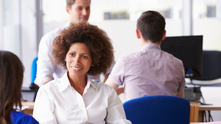 A smiling woman talking to her colleague