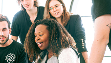 A group of colleagues around a laptop looking excited