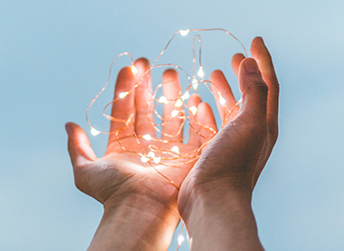 Two hands holding fairy lights