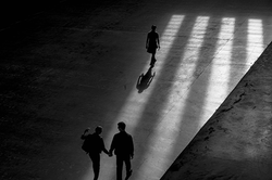 Three people walking inside a building casting shadows