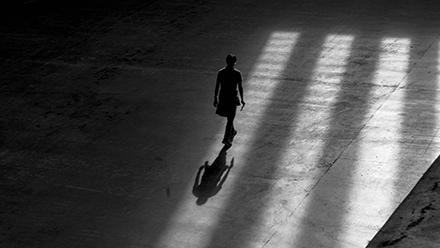 Three people walking inside a building casting shadows