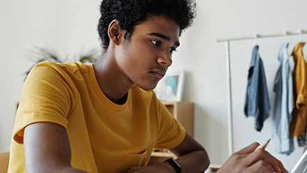 Young man in a yellow t-shirt working on a laptop