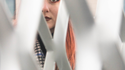 Woman looking through a patterned grid fence