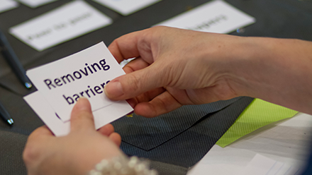 Hands holding a card that reads Removing Barriers