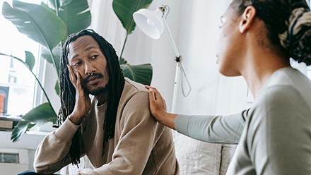 Man who looks worried being comforted by a friend